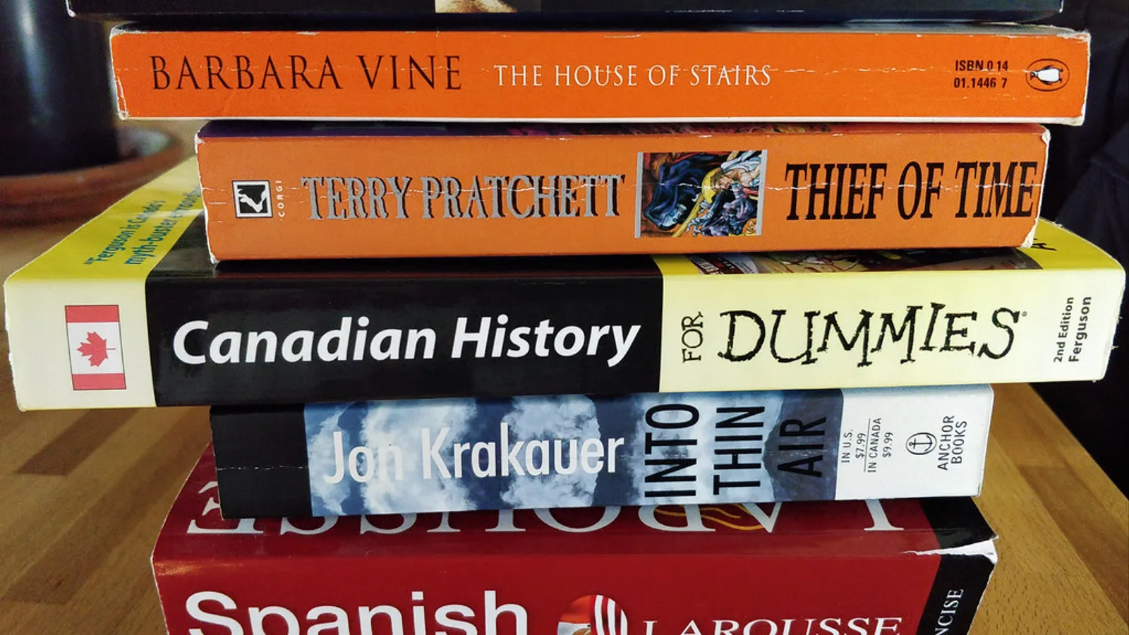 Stack of Spanish books to learn Spanish, including a grammar textbook and dictionary, on a desk